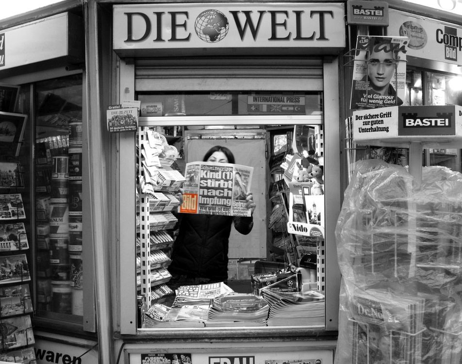 Kiosk Verkäuferin lacht verdeckt Gesicht mit Zeitung