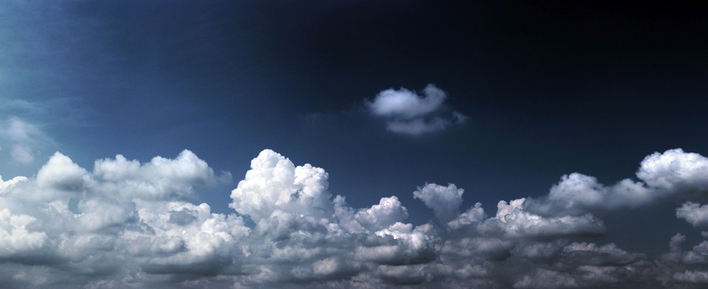 Mystisch dunkler blauer Himmel mit Cumulus Wolken